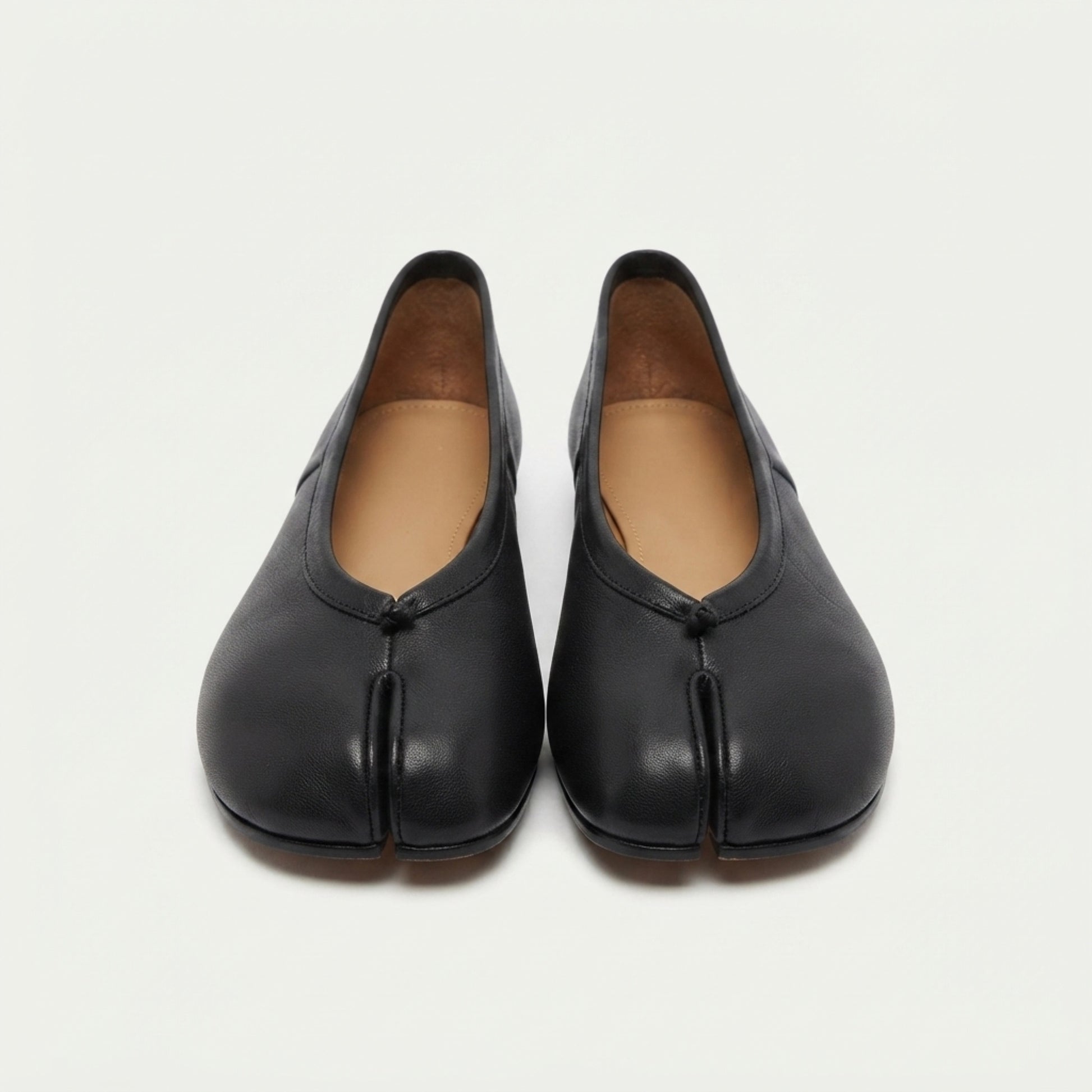 A pair of black leather tabi shoes with a traditional split-toe design, shown from the front on a light off-white background.